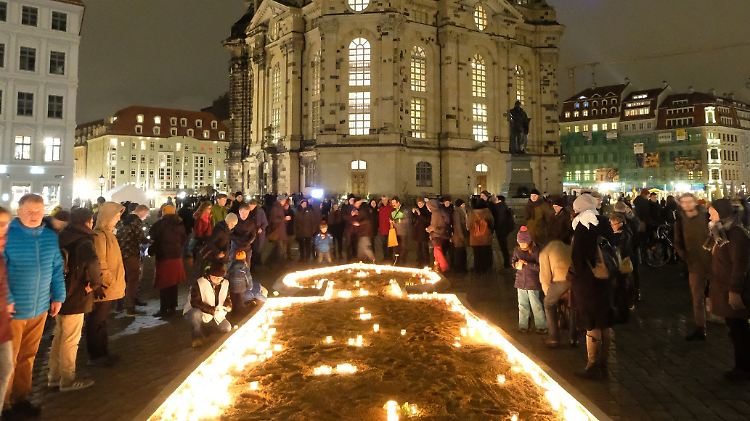 Dresdner und Gäste der Stadt versammeln sich auf dem Neumarkt vor der Frauenkirche und stellen Kerzen auf den Boden.