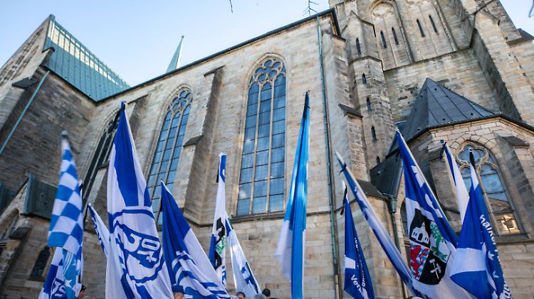 Über der Sankt Urbanus Kirche königsblauer Himmel, vor der Kirche königsblaue Fahnen: Gelsenkirchen nimmt Abschied.