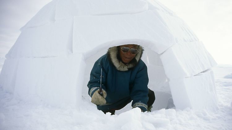 Ein Inuit zeigt, wie man ein Iglu baut.