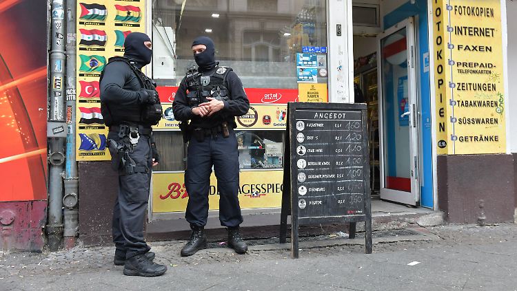 Zwei Einsatzkräfte stehen vor einem Kiosk im Berliner Stadtteil Neukölln.