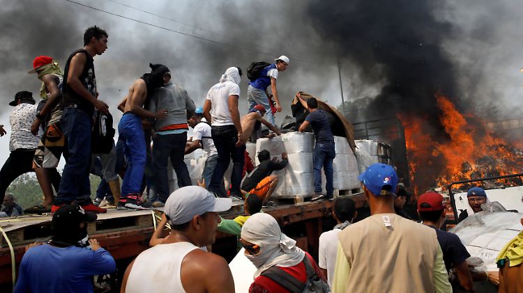Oppositionsanhänger versuchen Hilfsgüter von einem Lkw zu entladen, den Unterstützer der venezolanischen Regierung in Brand gesetzt haben. 