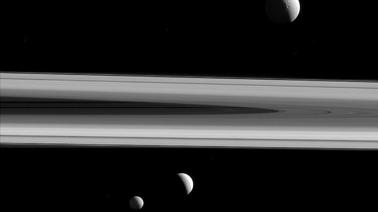 Saturn mit seinen Monden Tethys (oben), Enceladus (unten Mitte) und Mimas (unten links).
