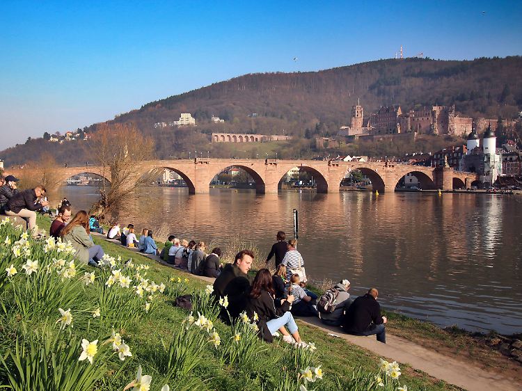 Prachtwetter mit Prachtaussicht: Am Heidelberger Neckarufer genießen die Menschen den Blick auf Wasser und Schloss.