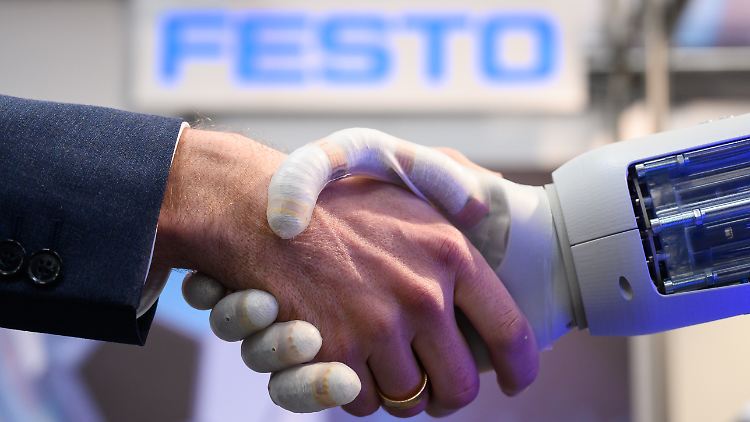 Roboter müssen nicht mehr versteckt werden: Am Stand der Unternehmensgruppe Festo schüttelt ein Roboter einem Mann die Hand.