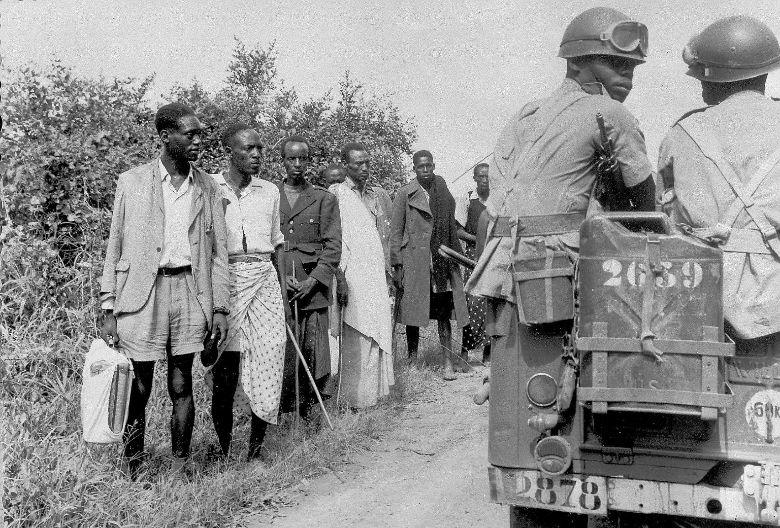 Der Völkermord an den Tutsi in Ruanda hat eine lange Vorgeschichte, die schon zu Kolonialzeiten begann. Die Deutschen und später die belgischen Kolonialherren haben die Unterscheidung zwischen Tutsi und Hutu eingeführt. (Das Bild zeigt Soldaten, die im November 1959 in Kigali Gefangene bewachen, die nach Kämpfen zwischen Tutsi und Hutu festgenommen wurden.)