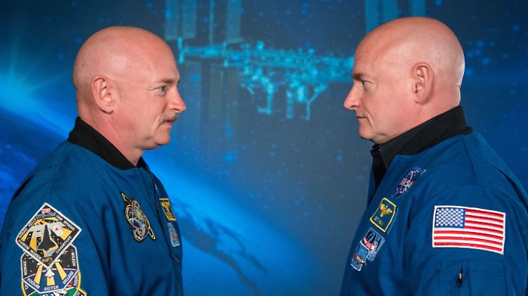Mark und Scott Kelly stehen sich in Astronauten-Kleidung gegenüber.