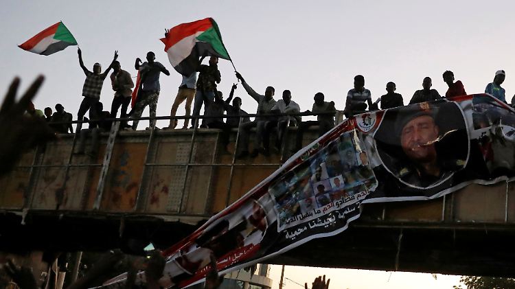 Demonstranten reißen ein Plakat von General Al-Burhan herunter. Sie fordern eine zivile Regierung.