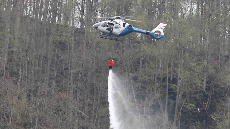 Ein Polizeihubschrauber bei Löscharbeiten im Wald an der Bleilochtalsperre.
