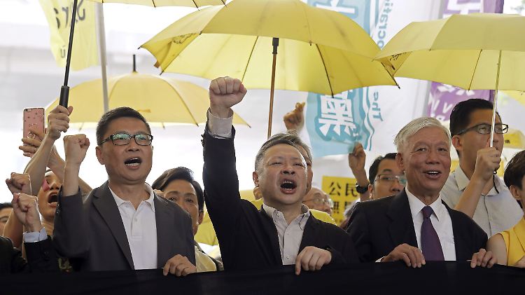Die Anführer der "Regenschirm-Bewegung", Chan Kin Man (links) und Benny Tai rufen Parolen, bevor das Gericht ihre Strafe verkündet: 16 Monate Haft.