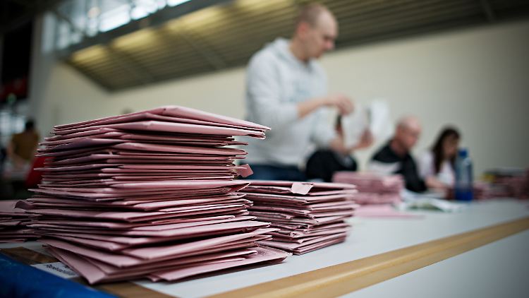 Wahlhelfer zählen Briefwahlunterlagen aus.