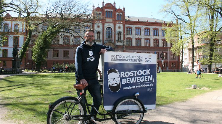 Claus Ruhe Madsen mit Lastenfahrrad und Werbe-Pulli vor der Universität Rostock: Der Däne möchte Oberbürgermeister werden.