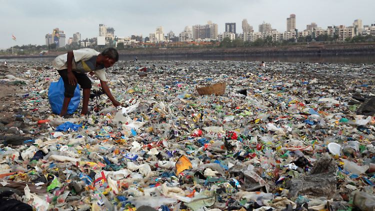 Plastikmüll-Pest: Ein Mann sammelt Wiederverwertbares an der von Plastiktüten und sonstigem Müll übersäten Küste vor Mumbai (Indien).