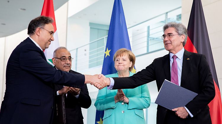 Im Beisein von Kanzlerin Merkel und dem irakischen Ministerpräsidenten Mahdi besiegeln Elektrizitätsminister Al-Khateeb (l.) und Siemens-Chef Kaeser ihren Deal.