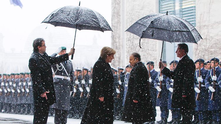 Empfang im dichten Schneetreiben: Merkel begrüßt Bouteflika (rechts, ohne Schirm).