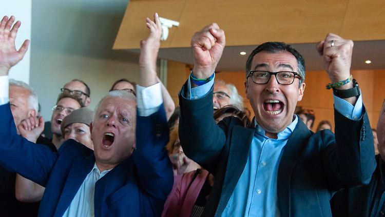 Die beiden Grünen-Politiker Fritz Kuhn, Oberbürgermeister von Stuttgart, und der Bundestagsabgeordnete Cem Özdemir (v.l.) jubeln im Rathaus nach Bekanntgabe der Wahlergebnisse.