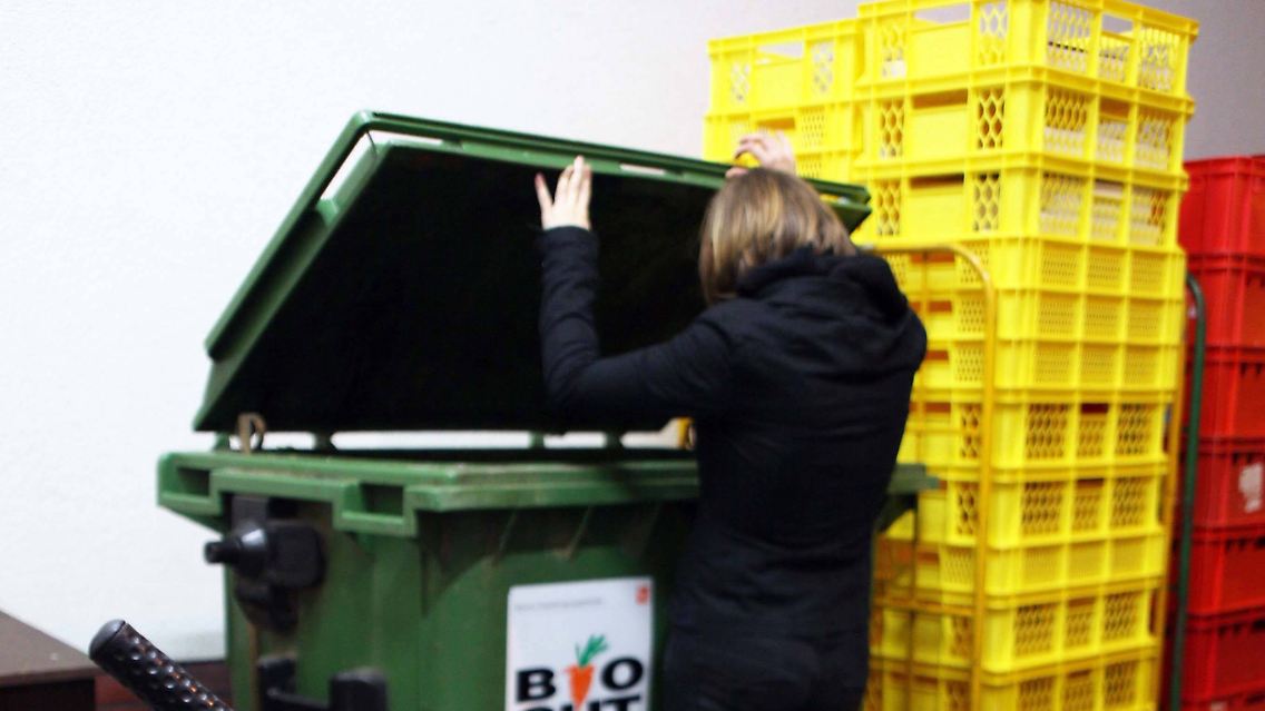 Eine Jugendliche sucht nachts nach Lebensmitteln in einer Bio-Tonne in Berlin.