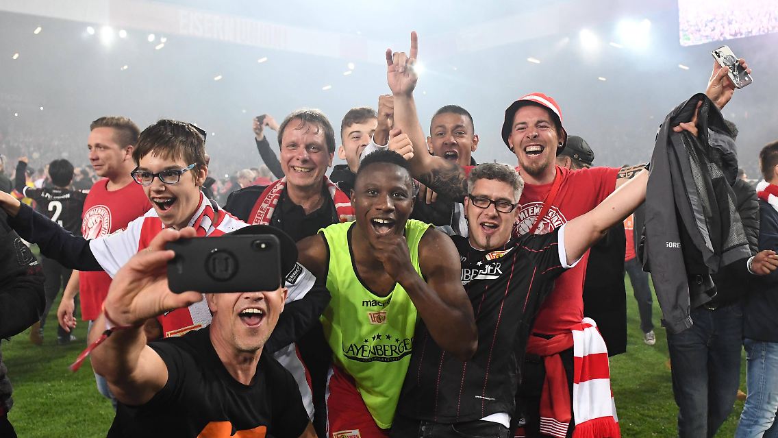 Geschafft: Union-Fans schnappen sich Suleiman Abdullahi nach der erfolgreichen Relegation für ein Party-Selfie auf dem Rasen im Stadion an der Alten Försterei.