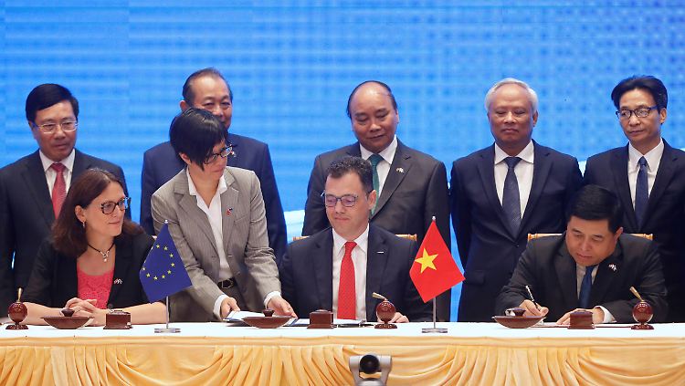 Cecilia Malmström (l.), EU-Kommissarin für Handel, und Tran Tuan Anh (r.), Handelsminister von Vietnam, tauschen die Dokumente, nachdem sie das Freihandelsabkommen beschlossen haben.