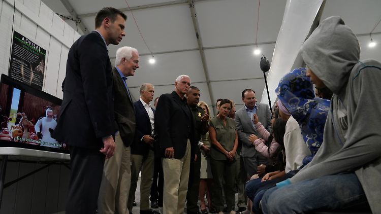 Mike Pence (m.) besucht die McAllen-Grenzstation - vor ihm sitzen die mutmaßlich illegalen Migranten.
