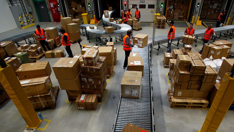 Amazon-Mitarbeiter im Logistikzentrum in Dortmund verfrachten fertige Pakete auf Fließbänder.