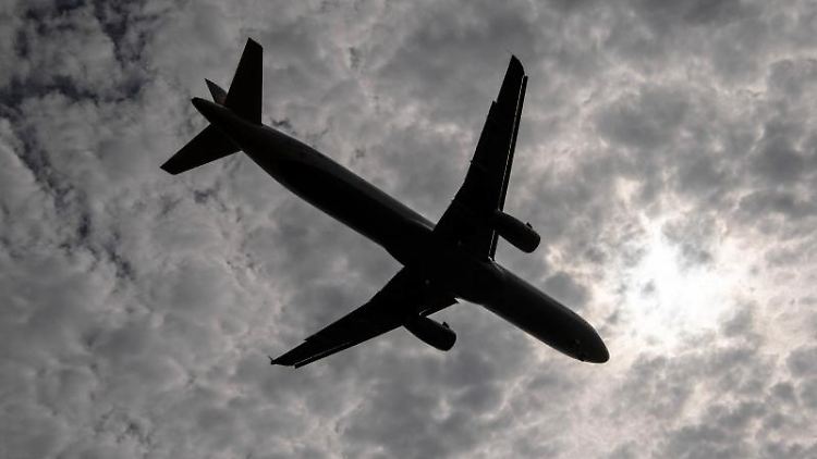 Vorbei an einem Wolkenfeld landet eine Passagiermaschine auf dem Flughafen. Foto: Boris Roessler/Archivbild