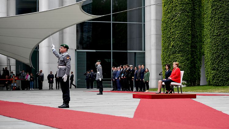 Die Kanzlerin und ihr Gast sitzen, während die Nationalhymnen gespielt werden.