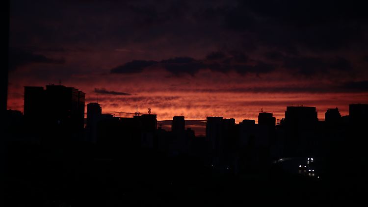 Die Sonne geht hinter dunklen Häusern in Caracas unter.