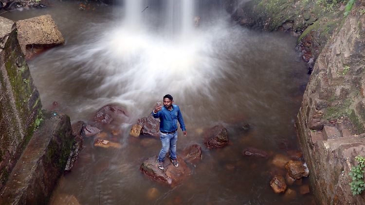 Ein indischer Tourist fotografiert sich auf einem Stein stehend vor einem Wasserfall: Spektakuläre Natur-Selfies sind beliebt.
