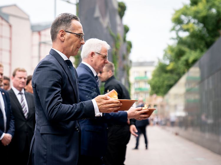 Außenminister Maas trägt neben seinem polnischen Amtskollegen Czaputowicz eine Kerze zur Gedenkmauer.
