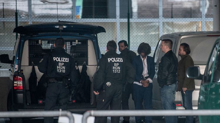 Polizeibeamte bringen einen gefesselten Ausreisepflichtigen zum Flugzeug.