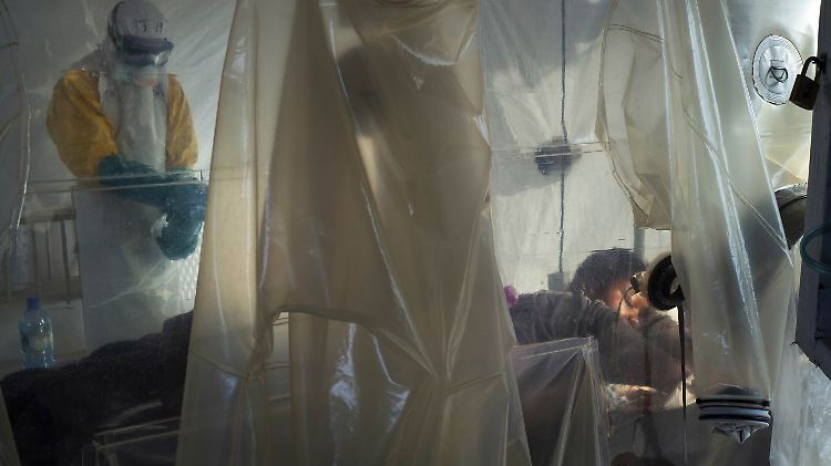 Gesundheitsfachkräfte überprüfen mit Schutzausrüstung einen Patienten, der in einem Kunststoffwürfel in einem Ebola-Behandlungszentrum in Beni, Kongo, isoliert ist.