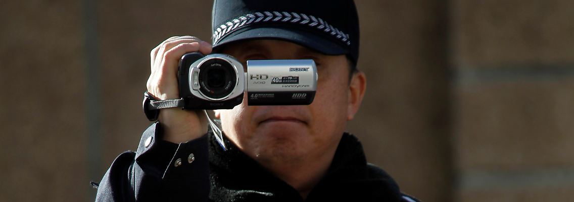 Ein chinesischer Polizist filmt Journalisten vor dem Gebäude der unter Hausarrest stehenden Ehefrau Liu Ciaobos.