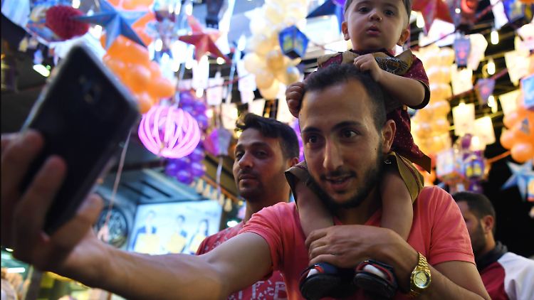 Besucher machen Selfies auf einem belebten Markt in Syriens Hauptstadt Damaskus.