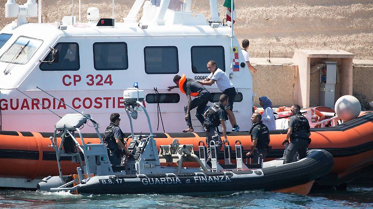 Beamte der italienischen Küstenwache bringen einen der Geflüchteten, die ins Meer gesprungen waren, an Land.