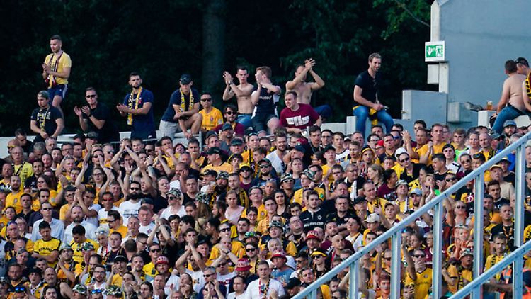 Dynamo-Fans sitzen im Darmstädter Gästeblock auf der äußeren Stadionmauer.