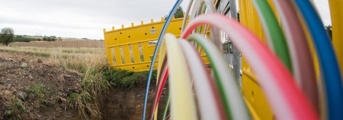 Leerrohre für Glasfaserleitungen für schnelles Internet liegen an einer Landstraße in der Baugrube. Foto: Julian Stratenschulte