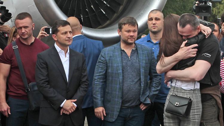 Der ukrainische Präsident Selenskyi (im weißen Hemd) schaut zu, wie Filmemacher Senzow (r.) von seiner Familie begrüßt wird.