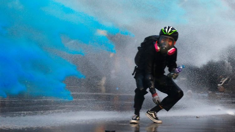 Wasserwerfer besprühen Demonstranten zur Markierung mit blauer Farbe.