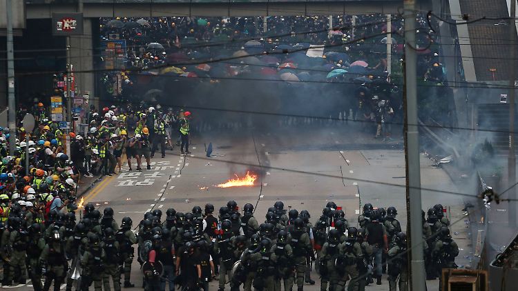Auf der Straße stehen sich gut ausgerüstete Polizisten und Demonstranten mit Brandsätzen gegenüber.