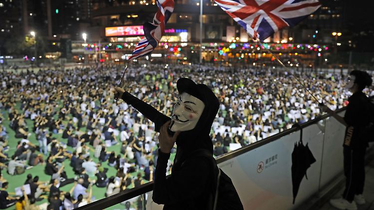 Demonstranten, die Guy-Fawkes-Masken tragen, schwenken die britische Nationalflagge in Hongkong.