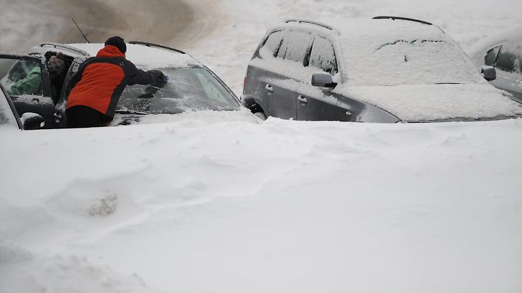 Ein Mann befreit in Spitzingsee (Oberbayern) sein Auto vom Schnee.