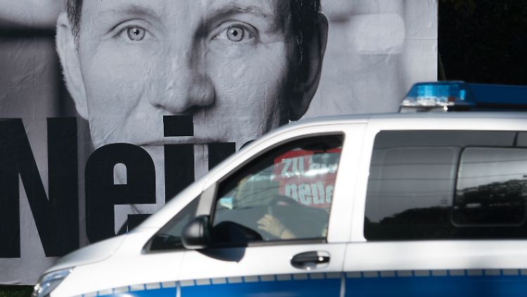Ein Polizeiauto passiert ein Linke-Plakat, das sich gegen Höcke richtet.