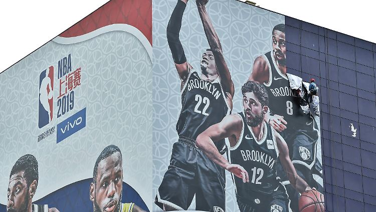 Ein Arbeiter entfernt ein NBA-Werbeposter in Schanghai.