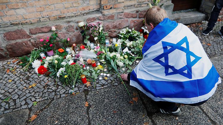 Ein Trauernder legt an der Synagoge in Halle Blumen nieder.