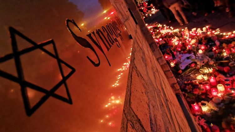 Menschen gedenken an der Synagoge von Halle des tödlichen Anschlags.