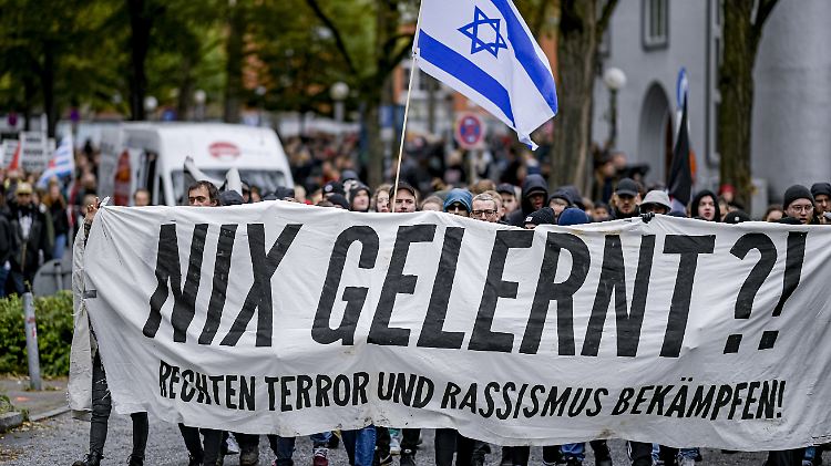 Teilnehmer einer Demonstration halten in Hamburg ein Banner mit der Aufschrift "Nix Gelernt - Rechten Terror und Rassismus bekämpfen" und eine israelische Fahne in die Höhe.