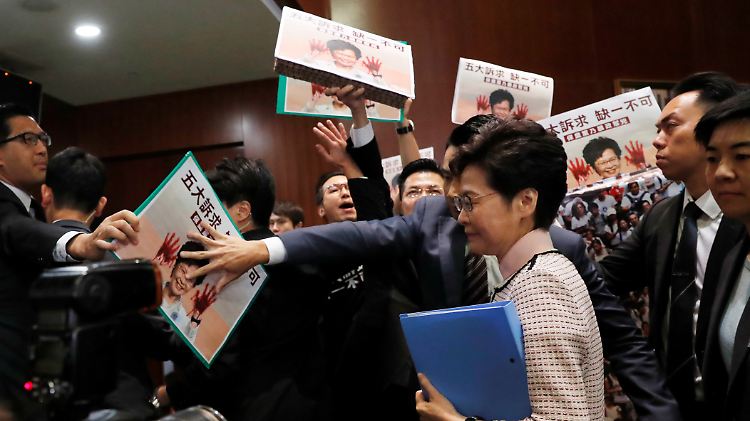 Unter Protesten versucht Hongkongs Regierungschefin Carrie Lam eine Regierungserklärung zu halten - und muss diese dann abbrechen.