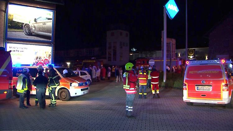 Feuerwehr und mutmaßliche Swinger-Club-Gäste (im Hintergrund) während des Einsatzes in Hattingen.