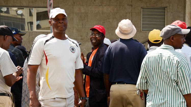 José Cossa steht im weißen Deutschland-Fußballtrikot vor dem Arbeitsministerium in Maputo.