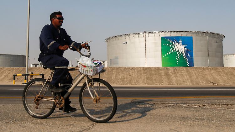 Ein Arbeiter radelt an einem Öltank von Aramco vorbei.